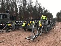 huomiovarusteisia sotilaita kokoaa metallirakennelmaa, taustalla kuorma-auto