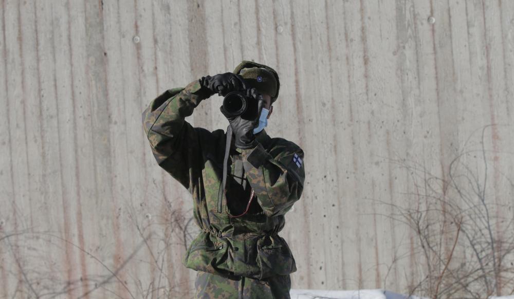 Varusmies katsoo kameran läpi kuvaajaa kohti.