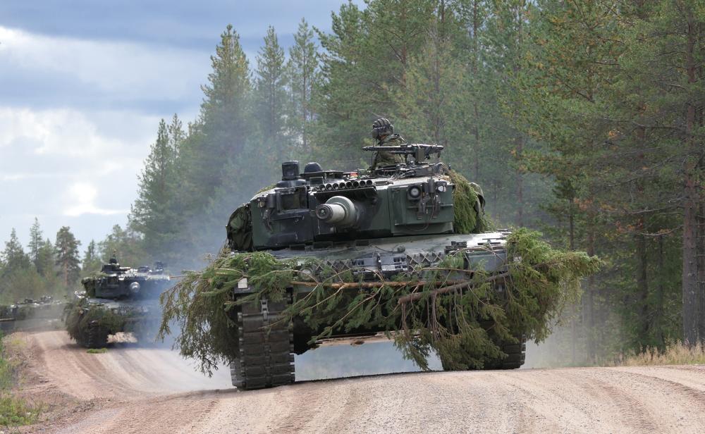 Kolme panssarivaunua etenee tiellä.