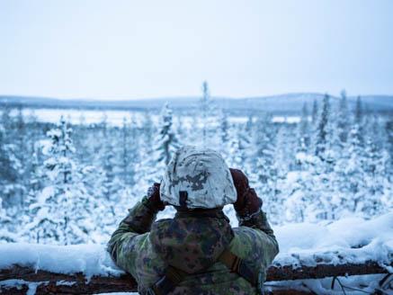 Kuva jossa tulenjohtaja tähystää maalialuetta kiikarilla.