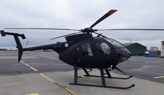 Musta MD500-helikopteri kentällä