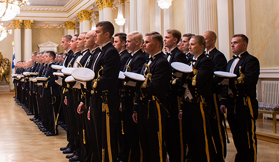 Kadetit seisovat nelirivissä lakit kädessä