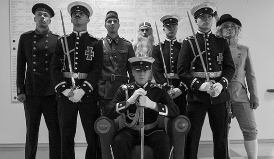 Ryhmäkuva kadeteista, osalla perinteisiä suomalaisia asusteita, tekopartoja ja peruukkeja