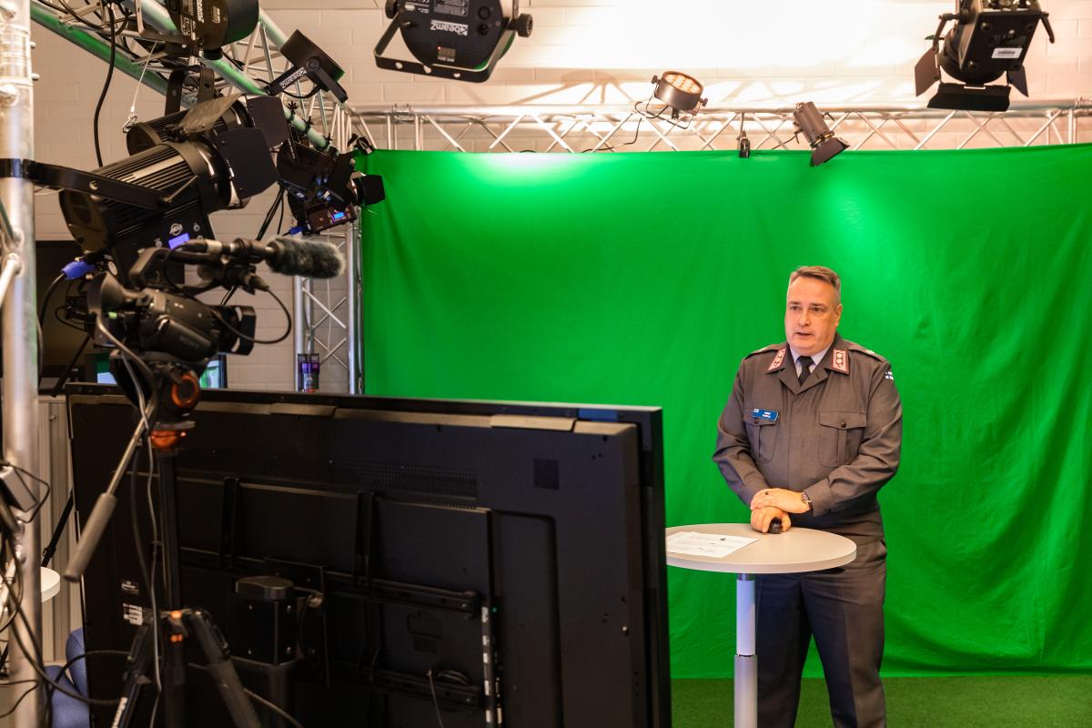 Kuvassa everstiluutnantti Harry Kantola vihreällä green screen -taustalla studiossa pitämässä luentoaan. Päällä upseerin kevyt palveluspuku.
