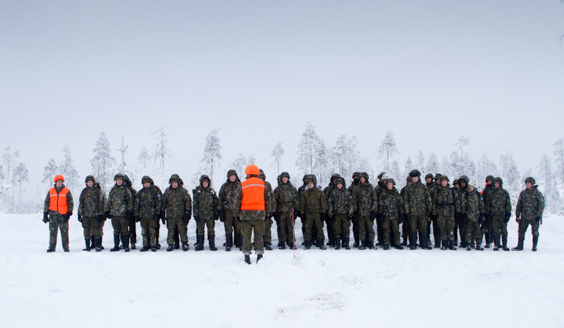 Sotilaita rivissä ja kouluttaja oranssissa liivissä heidän edessään