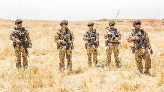 Viisi aseistettua sotilasta seisoo aavikolla 
