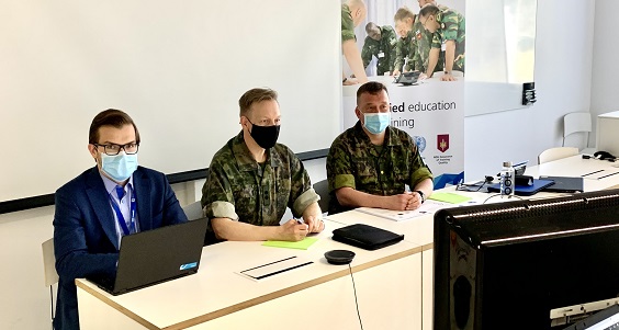 Thre men sitting behind a table wearing face masks